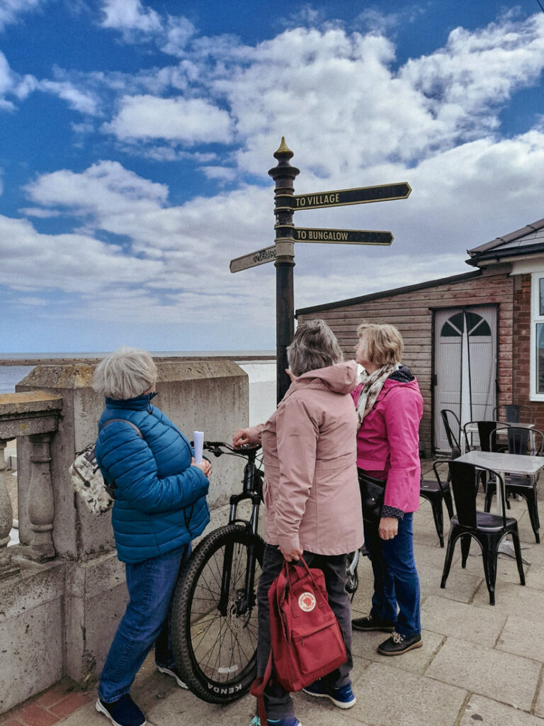 3 people signpost and coast